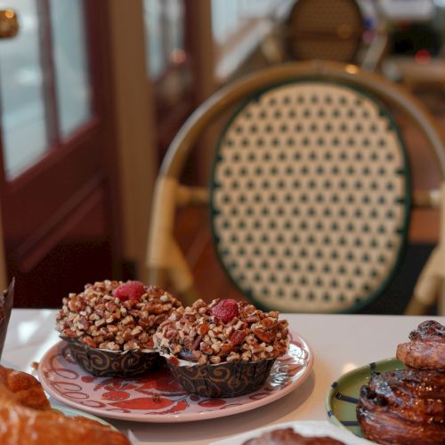 A cozy cafe table with assorted pastries and desserts on plates, plus blurred chairs and a Christmas tree in the background, festive mood.